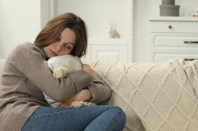 Sad young woman sitting on sofa at home, space for text