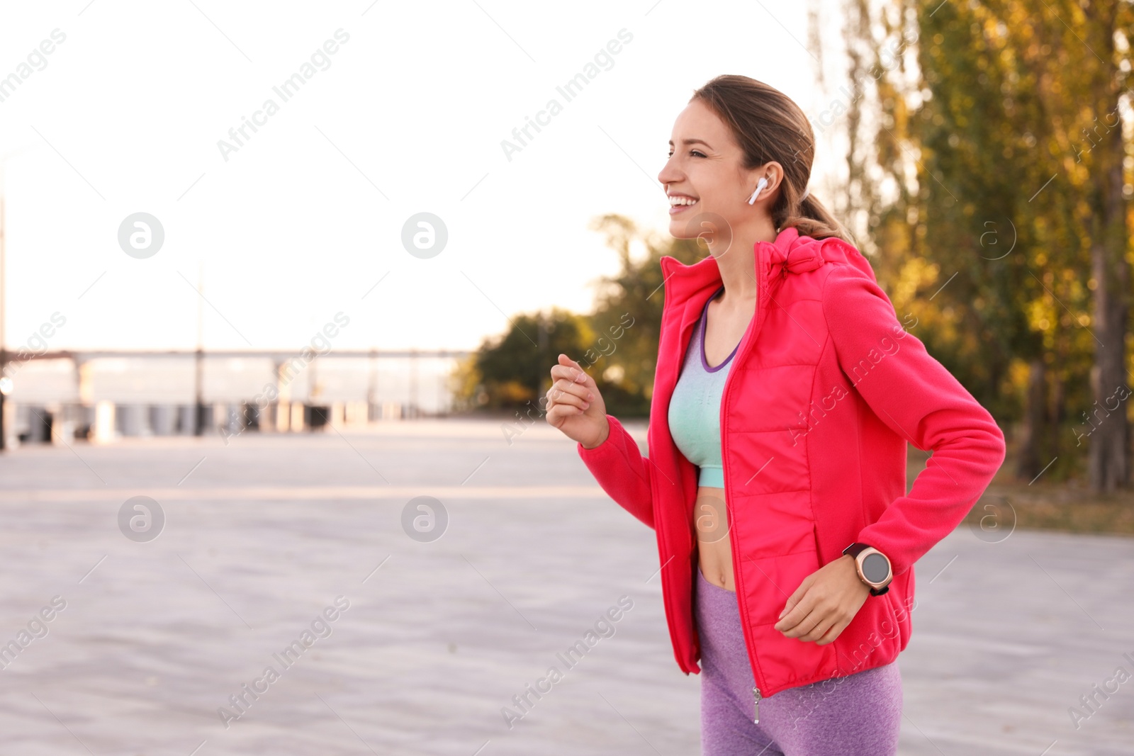 Photo of Young woman with wireless headphones listening to music outdoors. Space for text