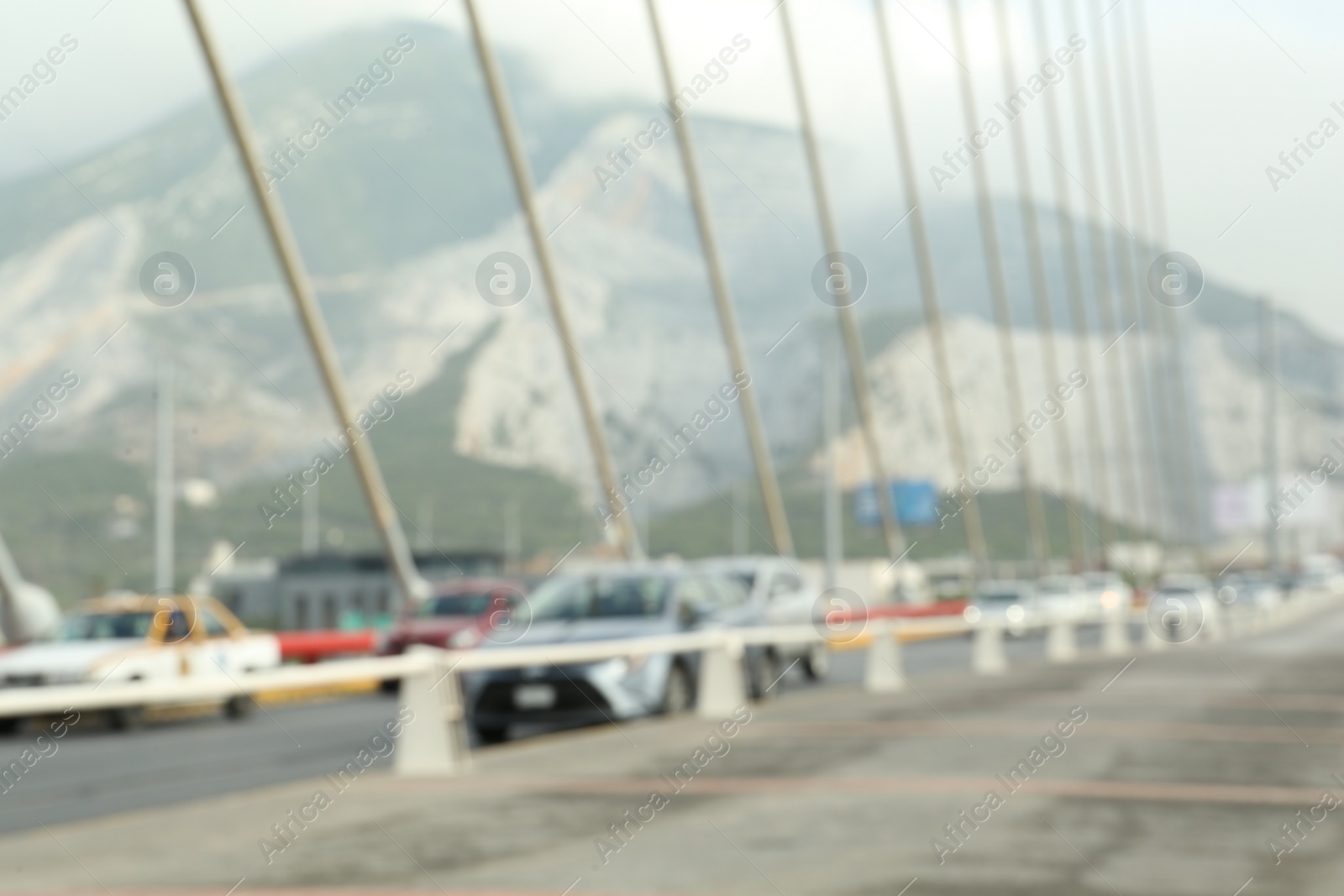 Photo of Blurred view of modern bridge and cars near mountain