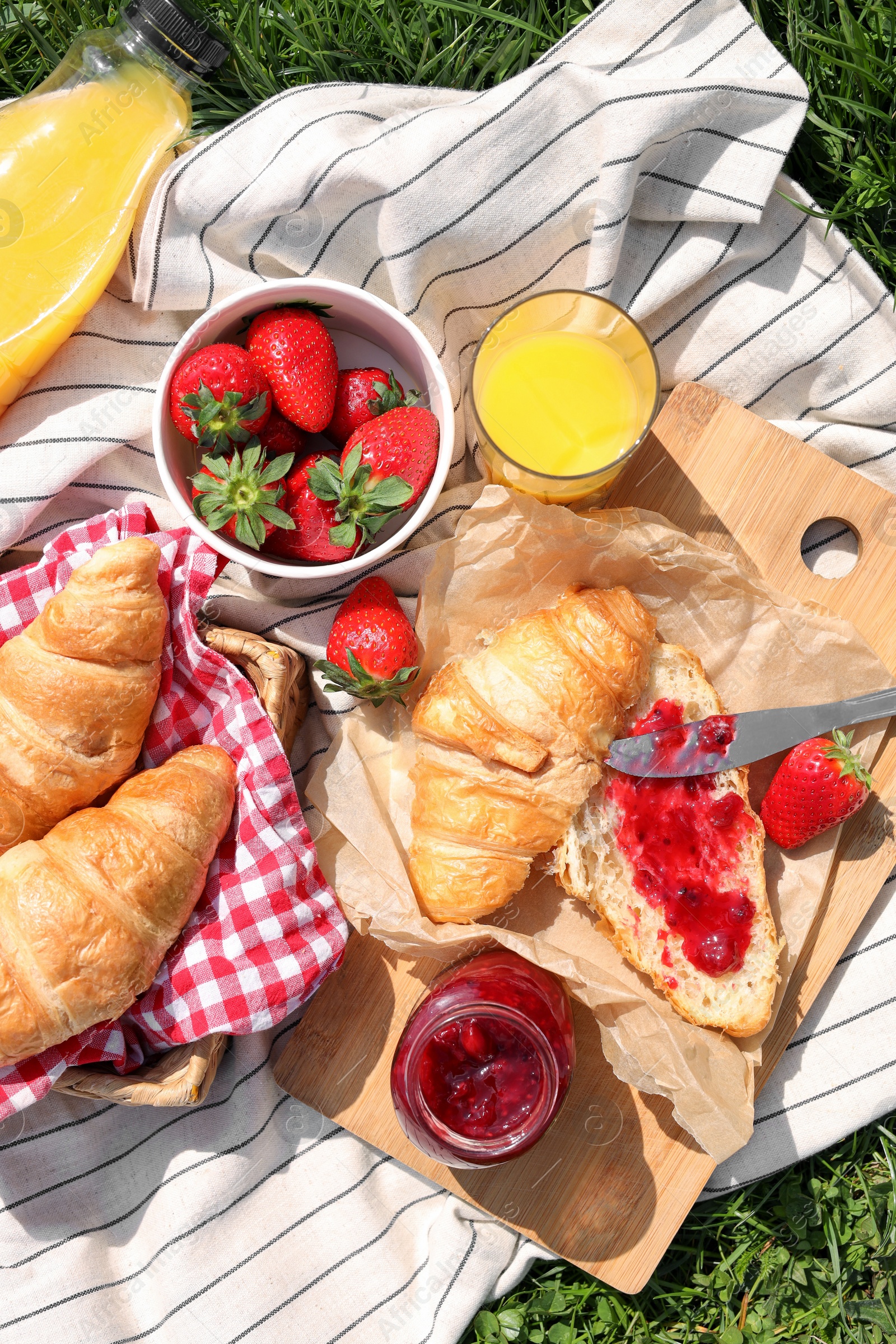 Photo of Blanket with different products on green grass, top view. Summer picnic