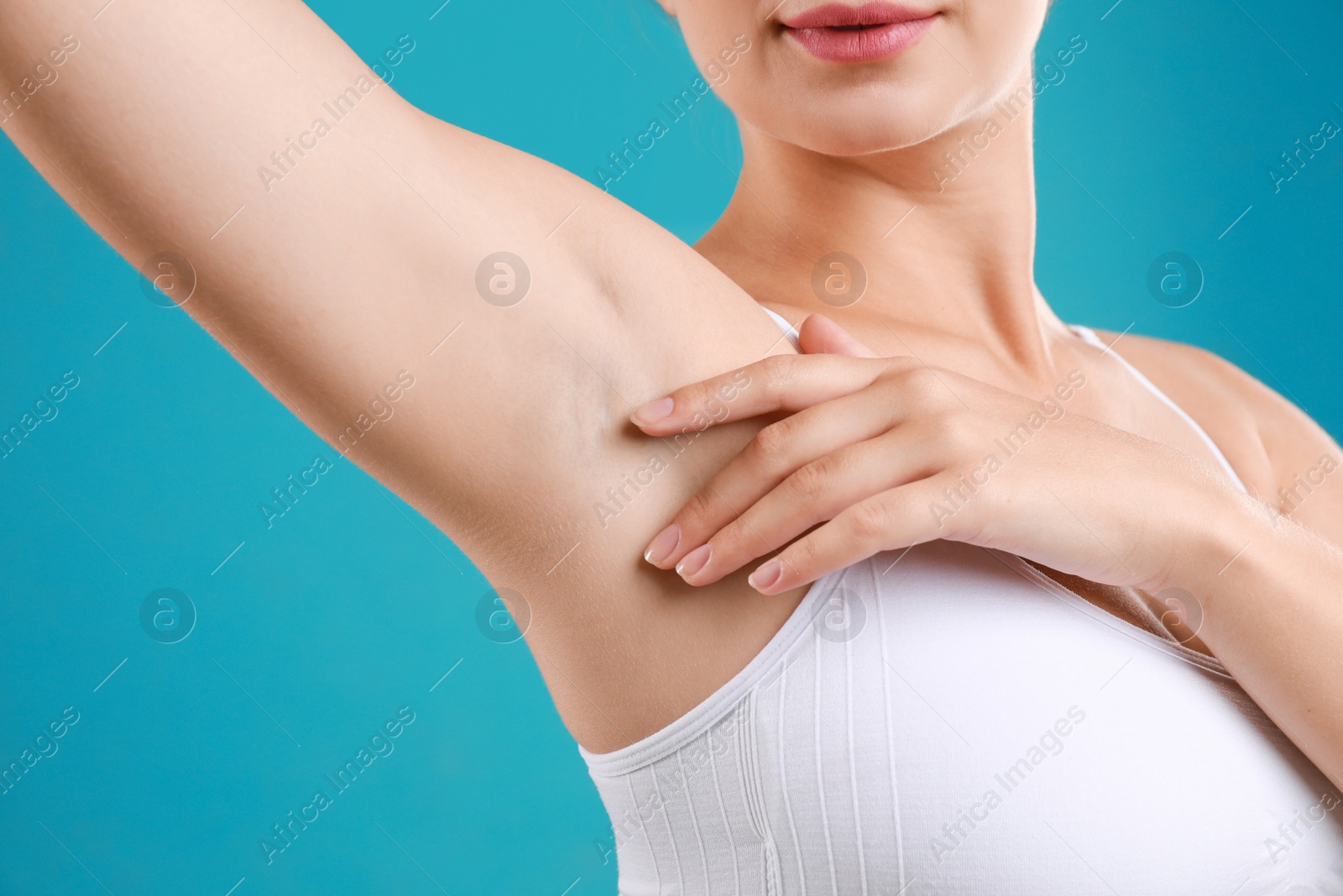 Photo of Young woman with smooth clean armpit on teal background, closeup. Using deodorant