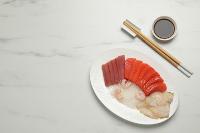 Tasty salmon slices, shrimp, funchosa and tuna on white marble table, flat lay with space for text. Delicious sashimi dish