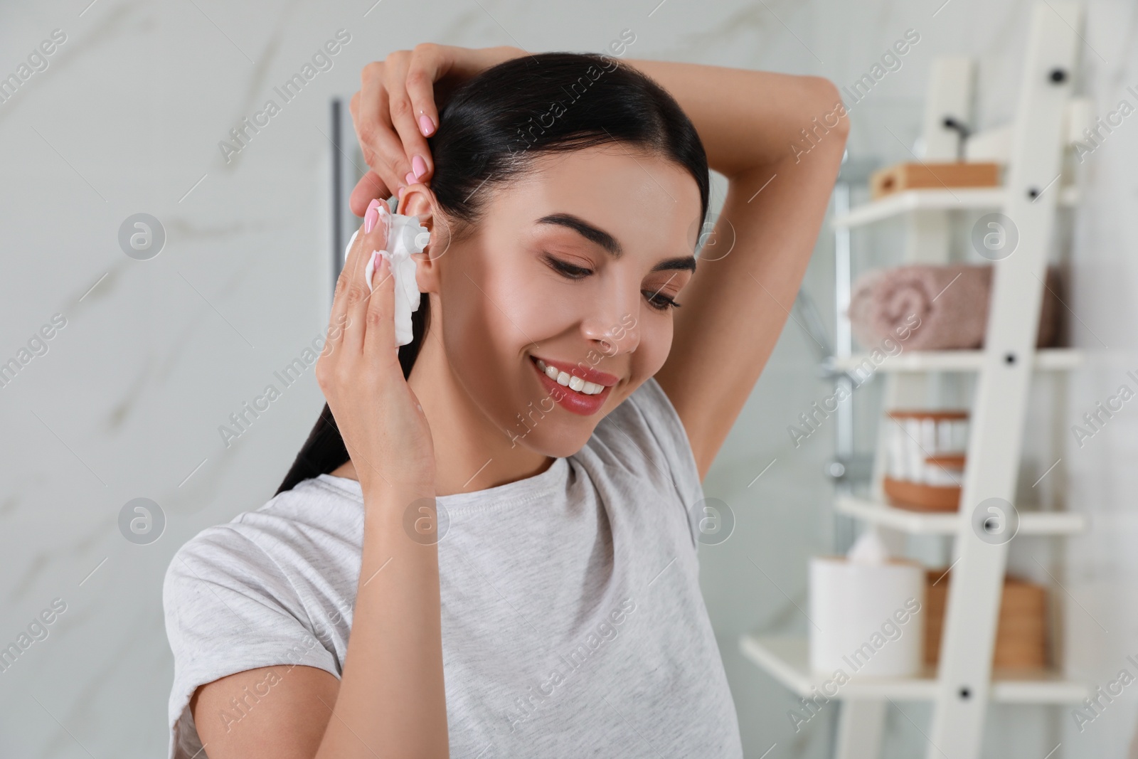 Photo of Woman applying dry shampoo onto her hair in bathroom