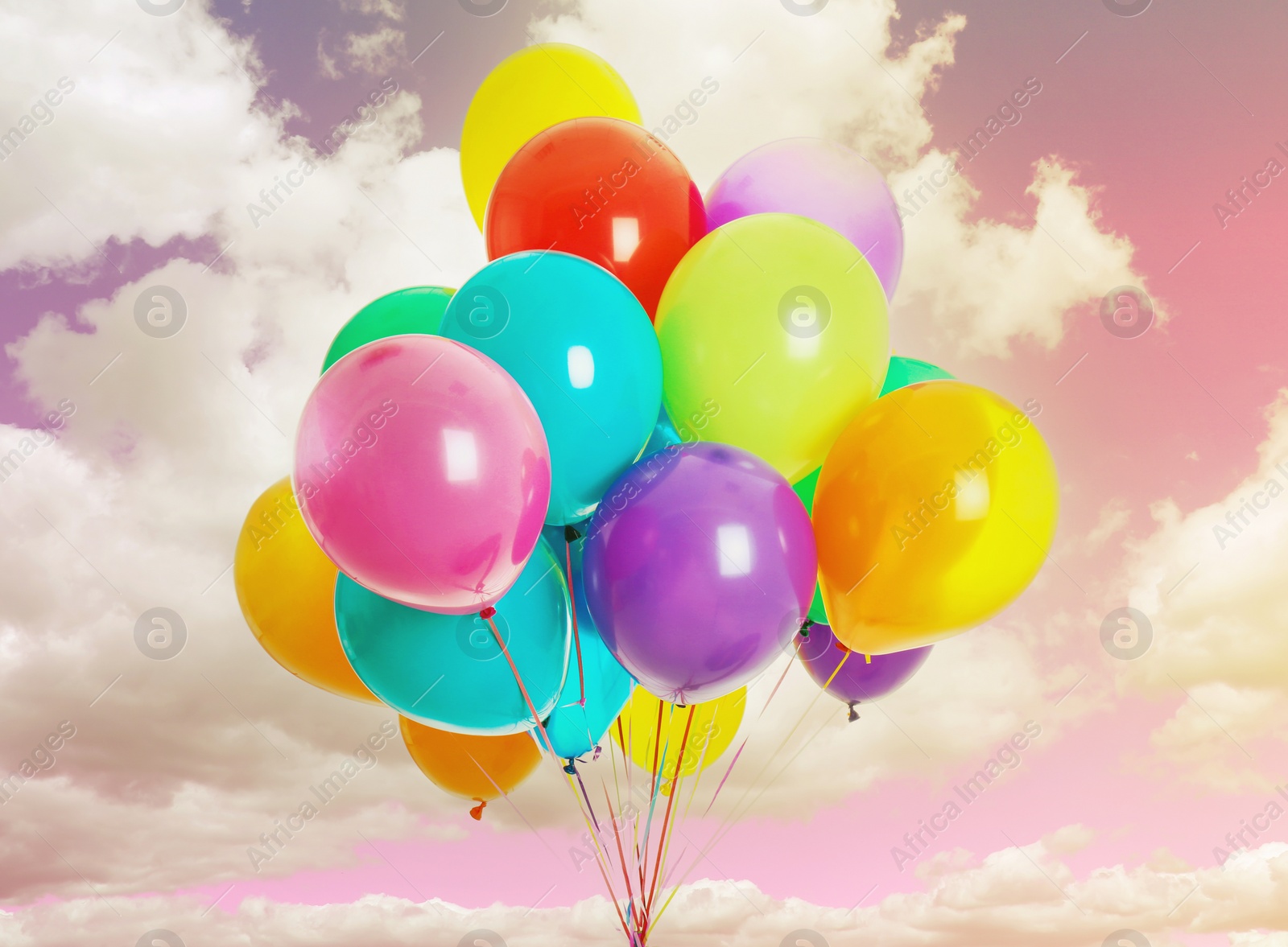 Image of Bunch of colorful balloons flying in pink sky with clouds, color toned