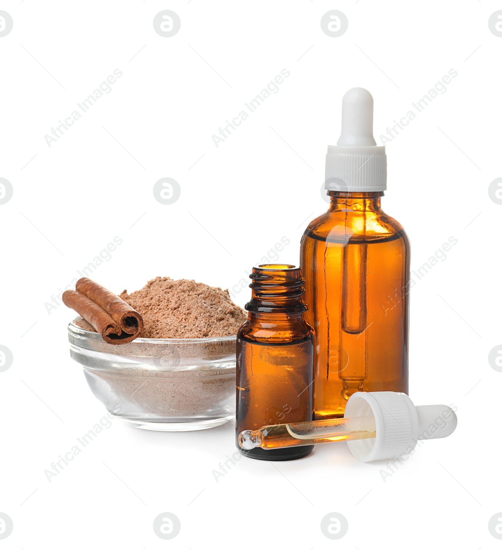 Photo of Bottles with cinnamon oil, powder and sticks on white background