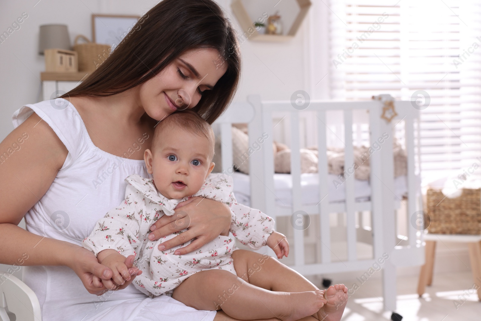 Photo of Happy young mother with her baby daughter in nursery. Space for text