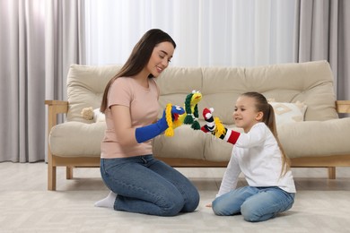 Photo of Happy mother and daughter playing with funny sock puppets together at home