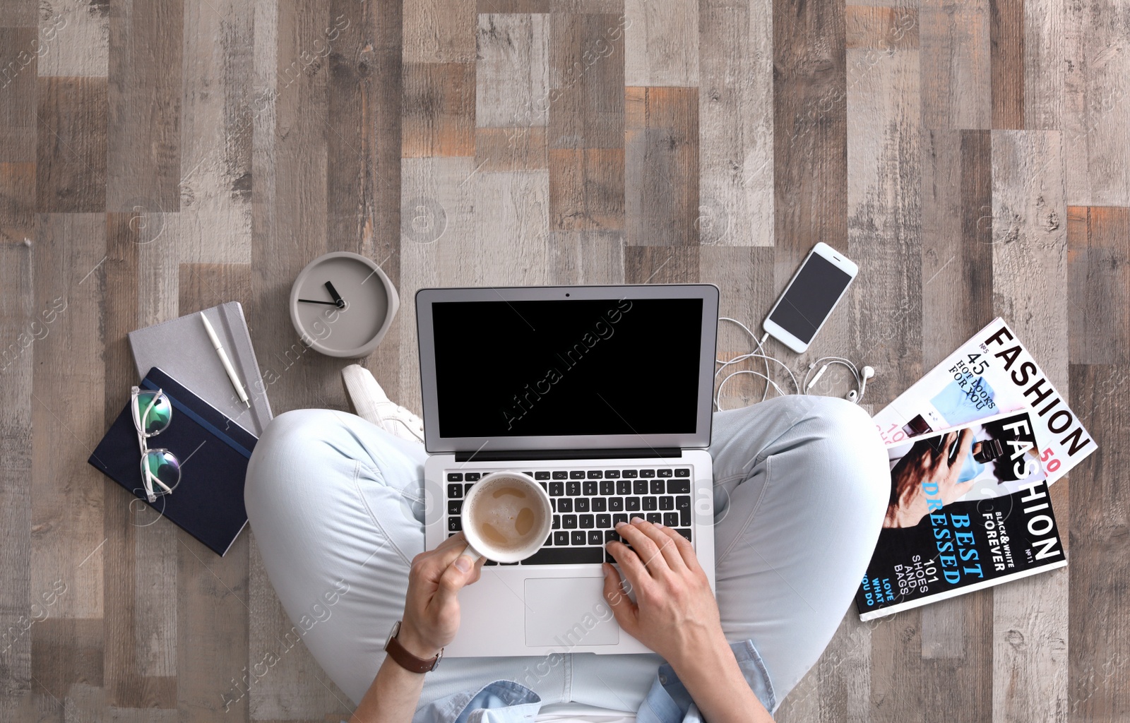 Photo of Young man with laptop and cup of coffee sitting on floor, top view