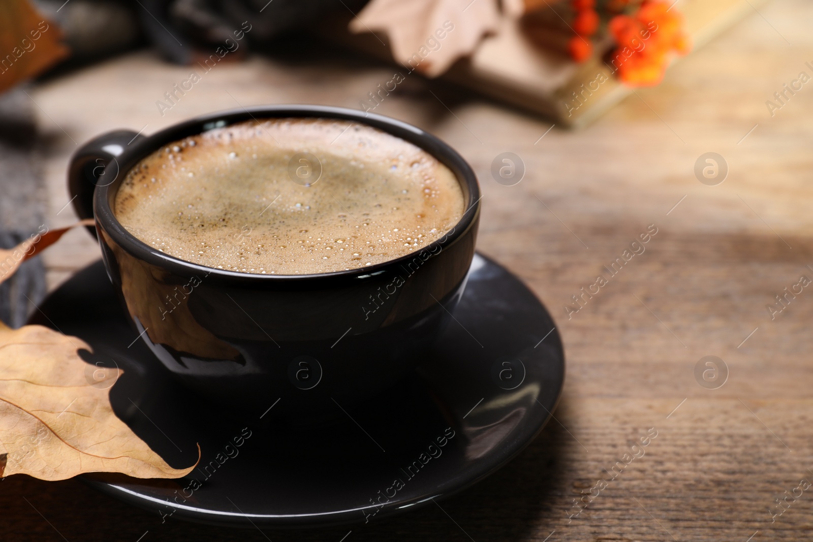 Photo of Cup with hot drink on wooden table, space for text. Cozy autumn