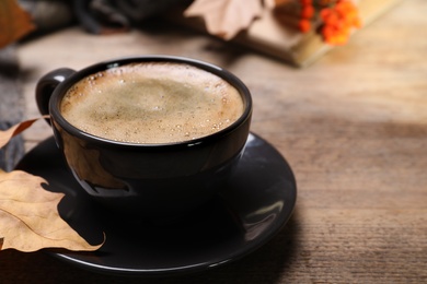 Cup with hot drink on wooden table, space for text. Cozy autumn