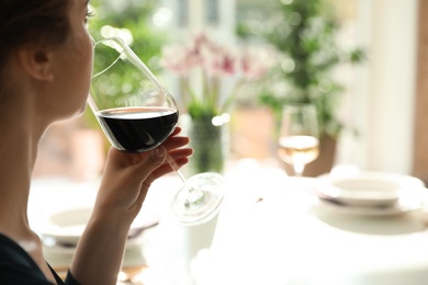 Woman with glass of wine in restaurant, closeup. Space for text