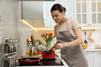 Woman cooking dinner on cooktop in kitchen