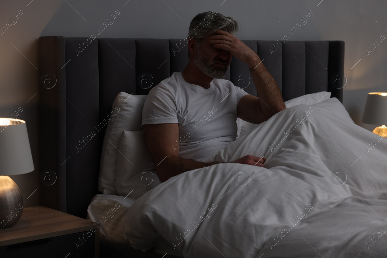 Photo of Mature man suffering from headache in bed at night