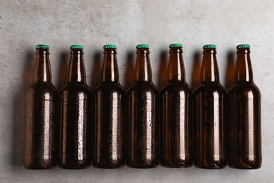 Photo of Glass bottles of beer on light grey background, flat lay