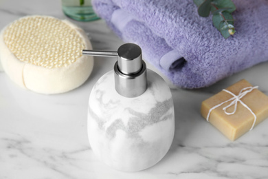 Photo of Soap dispenser and toiletries on white marble table