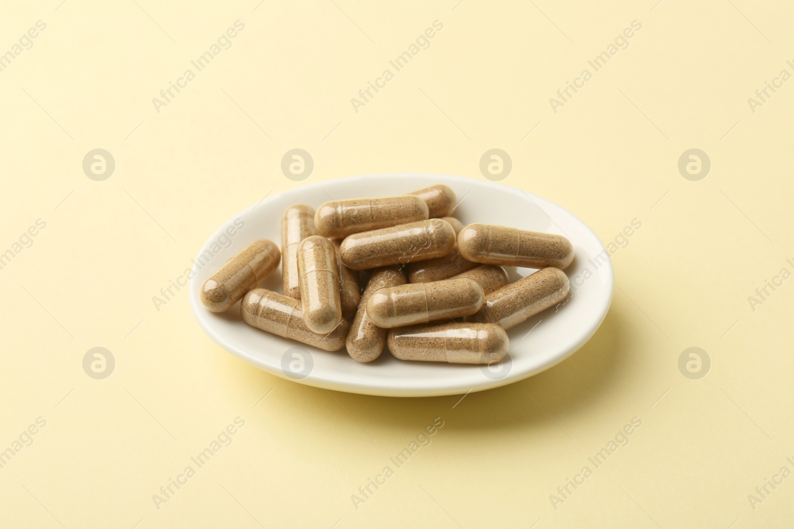 Photo of Vitamin capsules on pale yellow background. Health supplement