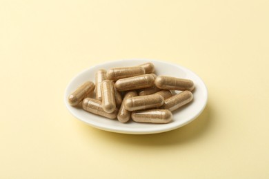 Vitamin capsules on pale yellow background. Health supplement