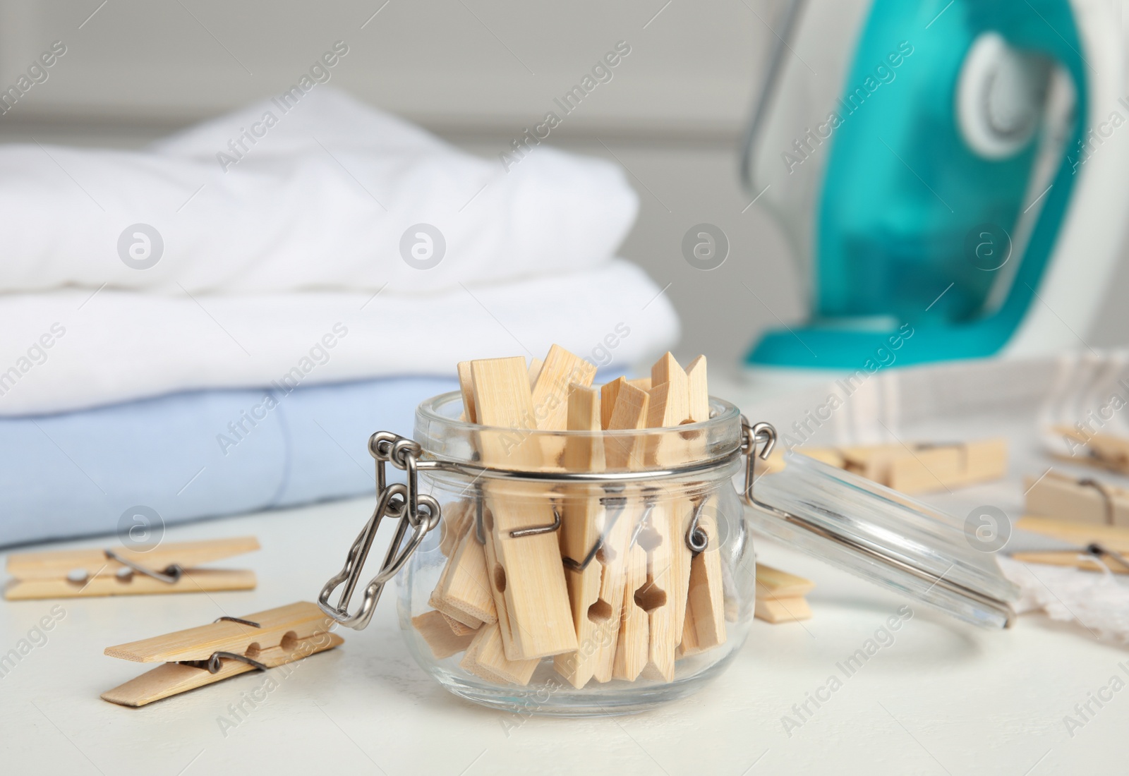 Photo of Many wooden clothespins and glass jar on white table