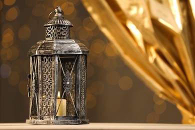 Arabic lantern on table against blurred lights, space for text