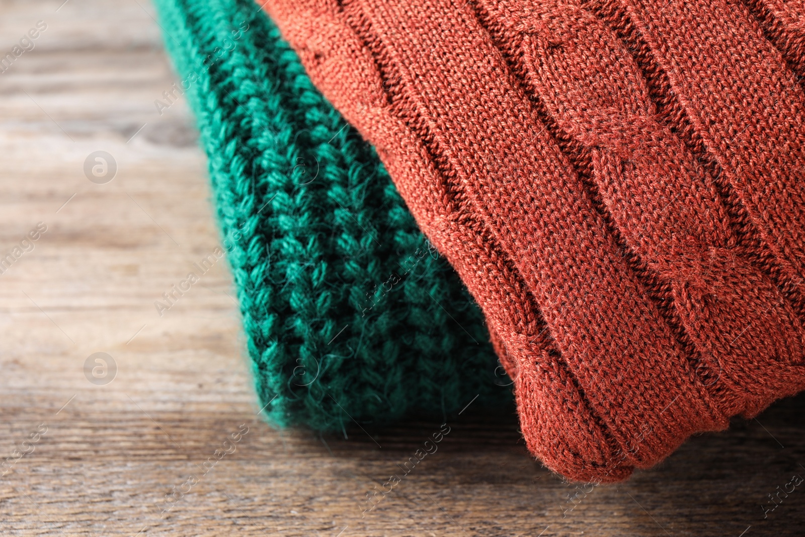 Image of Folded warm sweaters on wooden table, closeup