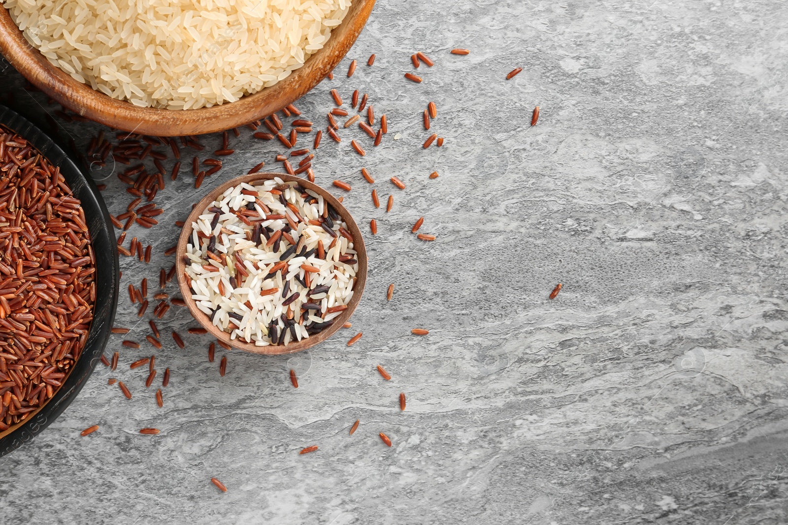 Photo of Flat lay composition with brown and other types of rice on grunge background. Space for text