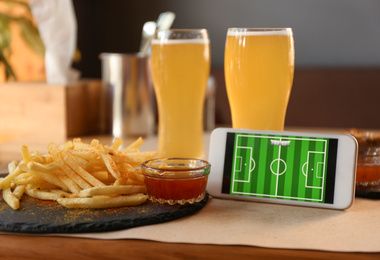 Tasty french fries and smartphone on table