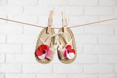 Photo of Cute baby shoes drying on washing line against white brick wall