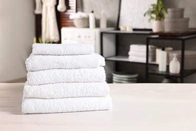 Photo of Stack of clean towels on white table in laundry room, space for text