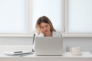 Tired young woman sleeping at workplace in office