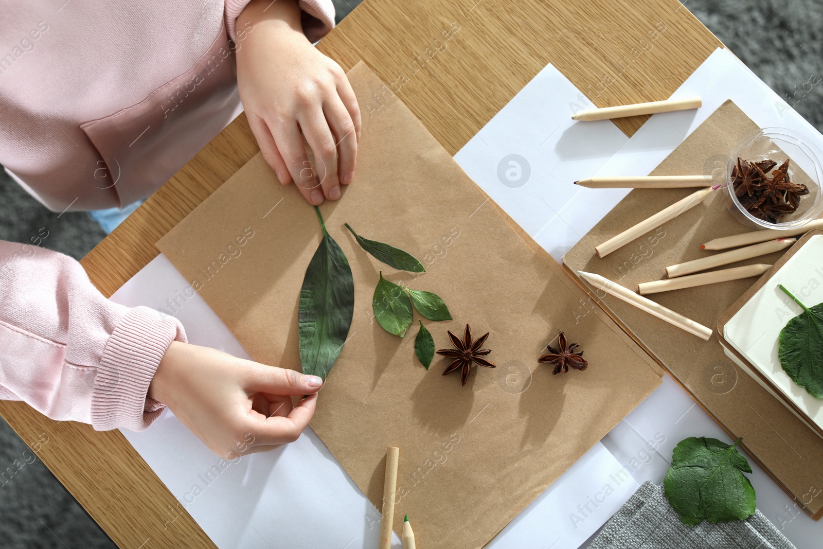 Photo of Little girl working with natural materials at table, top view. Creative hobby