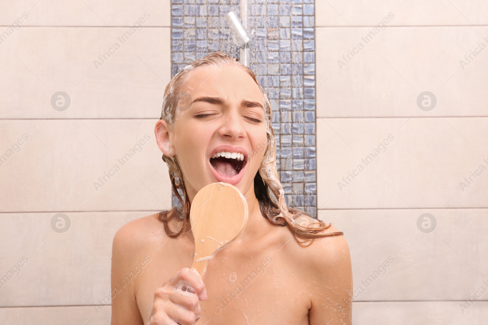 Photo of Beautiful young woman singing in shower at home