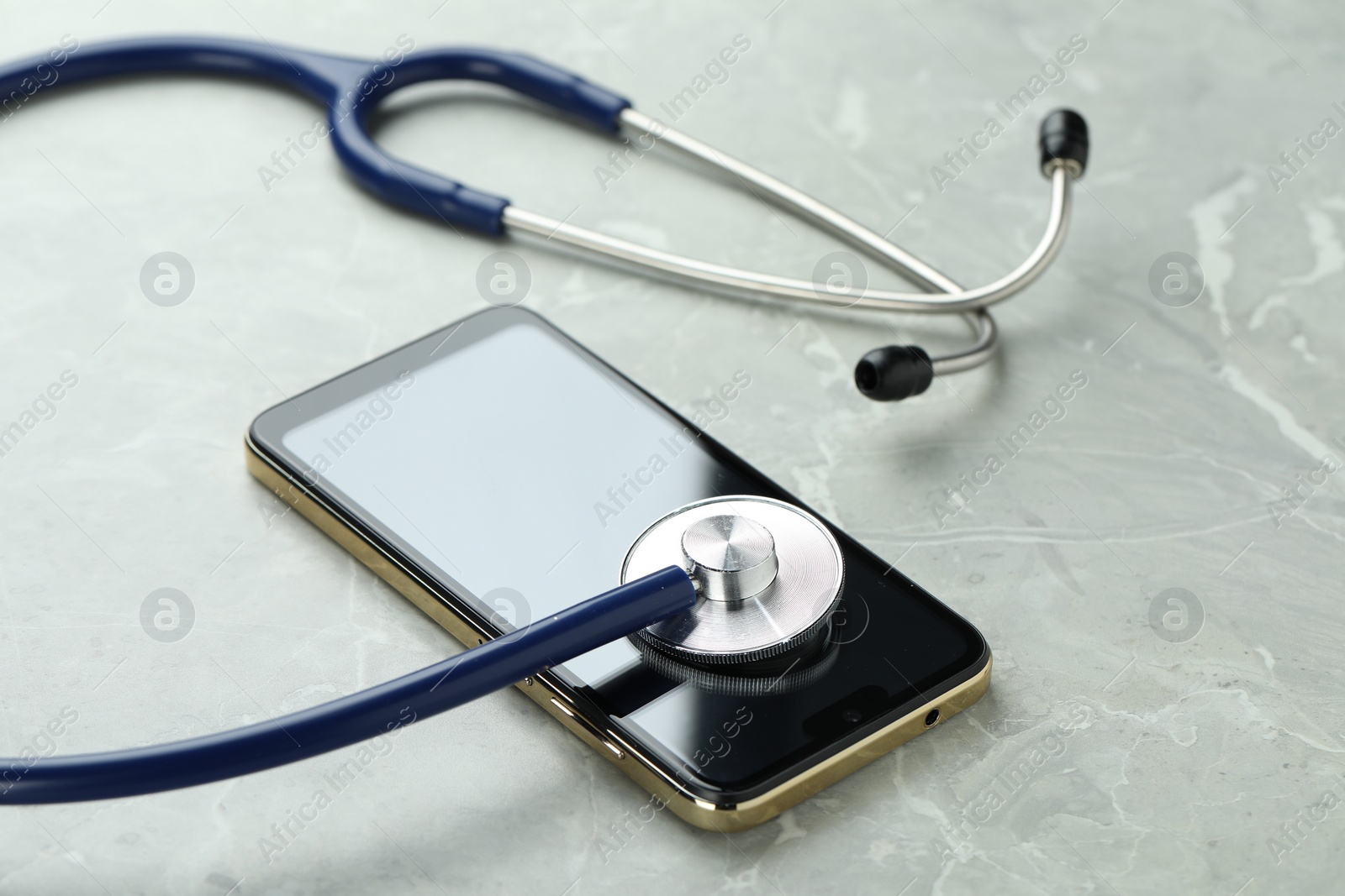 Photo of Modern smartphone and stethoscope on grey table