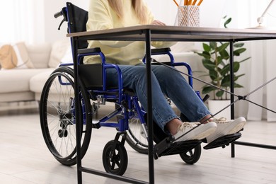 Photo of Woman in wheelchair at table indoors, closeup
