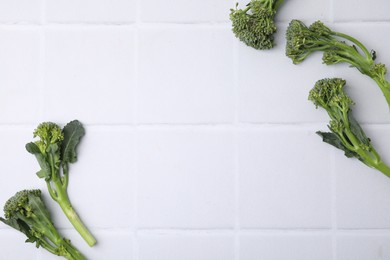 Photo of Fresh raw broccolini on white tiled table, flat lay and space for text. Healthy food