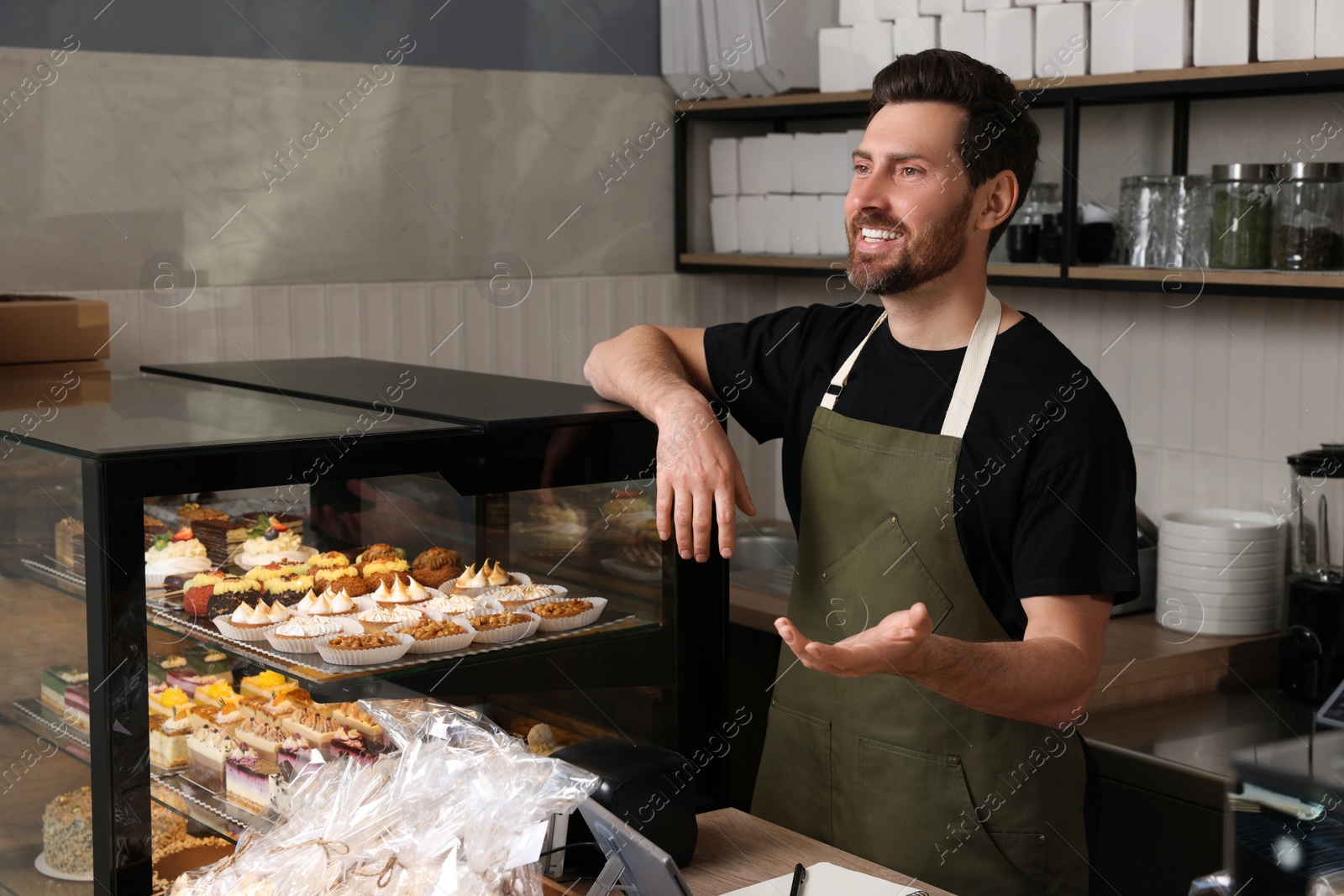 Photo of Portrait of happy seller at cashier desk in bakery shop