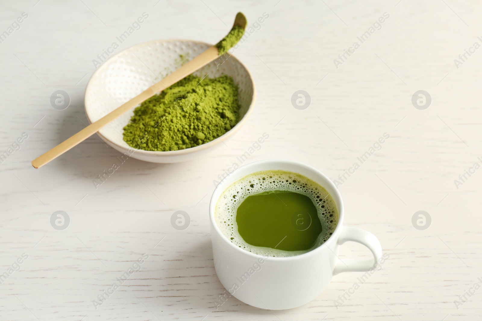 Photo of Cup of fresh beverage and chawan with powdered matcha tea on table