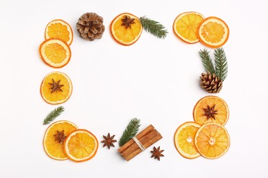 Photo of Frame made of dry orange slices, anise stars, fir branches and cones on white background, flat lay. Space for text