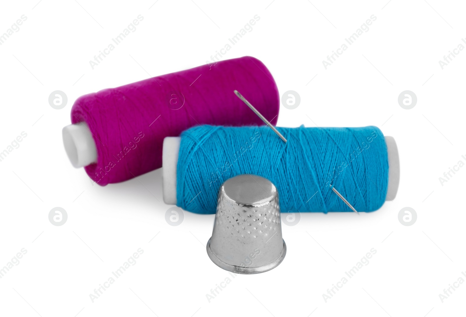 Photo of Thimble, spools of sewing threads and needle isolated on white