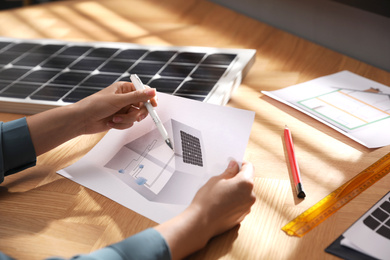 Photo of Woman working on house project with solar panels at table in office, closeup