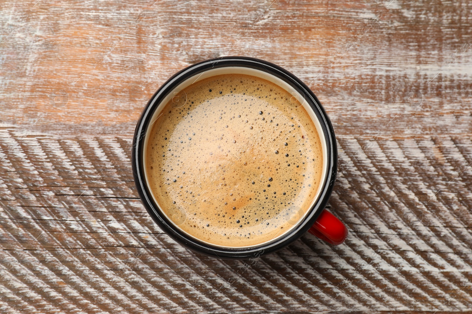 Photo of Cup of aromatic coffee on wooden table, top view