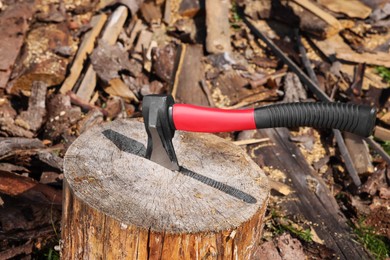 Photo of Tree stump with axe and cut firewood outdoors