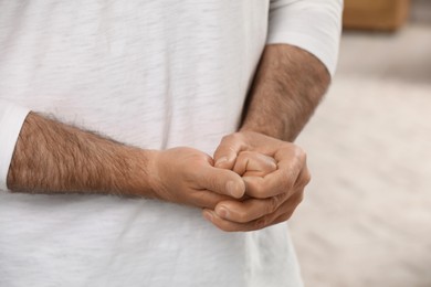 Photo of Man cracking his knuckles on blurred background, closeup. Bad habit