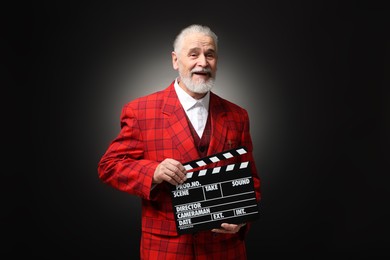 Photo of Senior actor with clapperboard on black background. Film industry