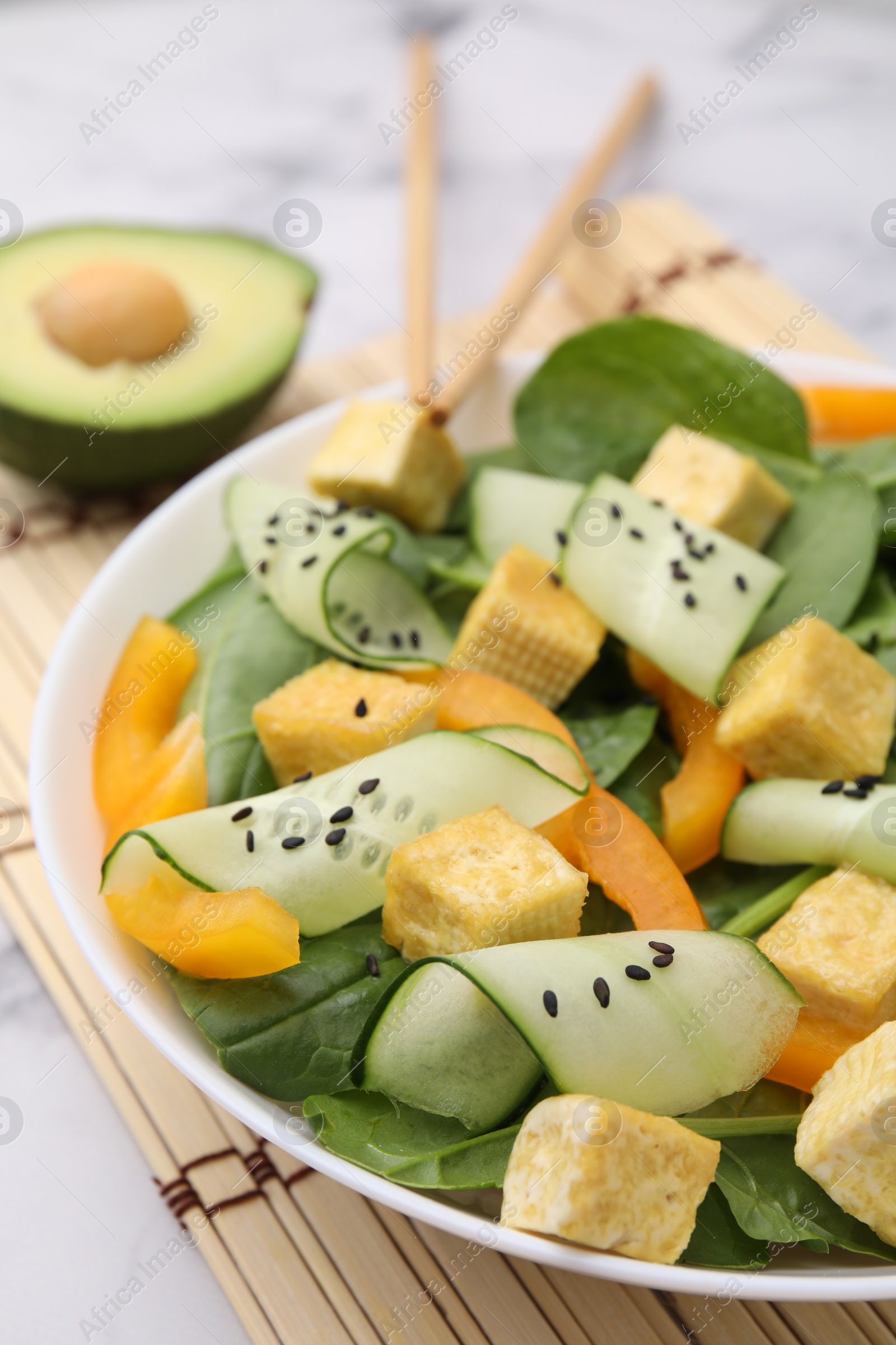 Photo of Bowl of tasty salad with tofu and vegetables on white marble table, closeup