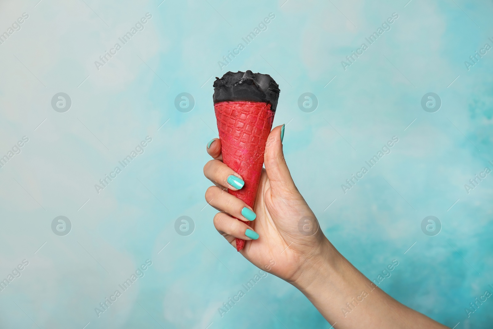 Photo of Woman holding yummy ice cream on color background. Focus on hand