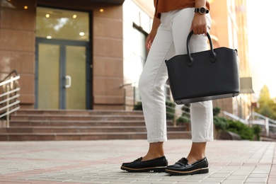 Young woman with stylish black bag on city street, closeup