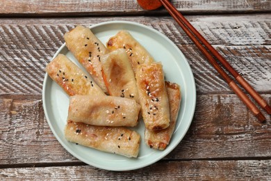 Photo of Tasty fried spring rolls served on wooden table, flat lay