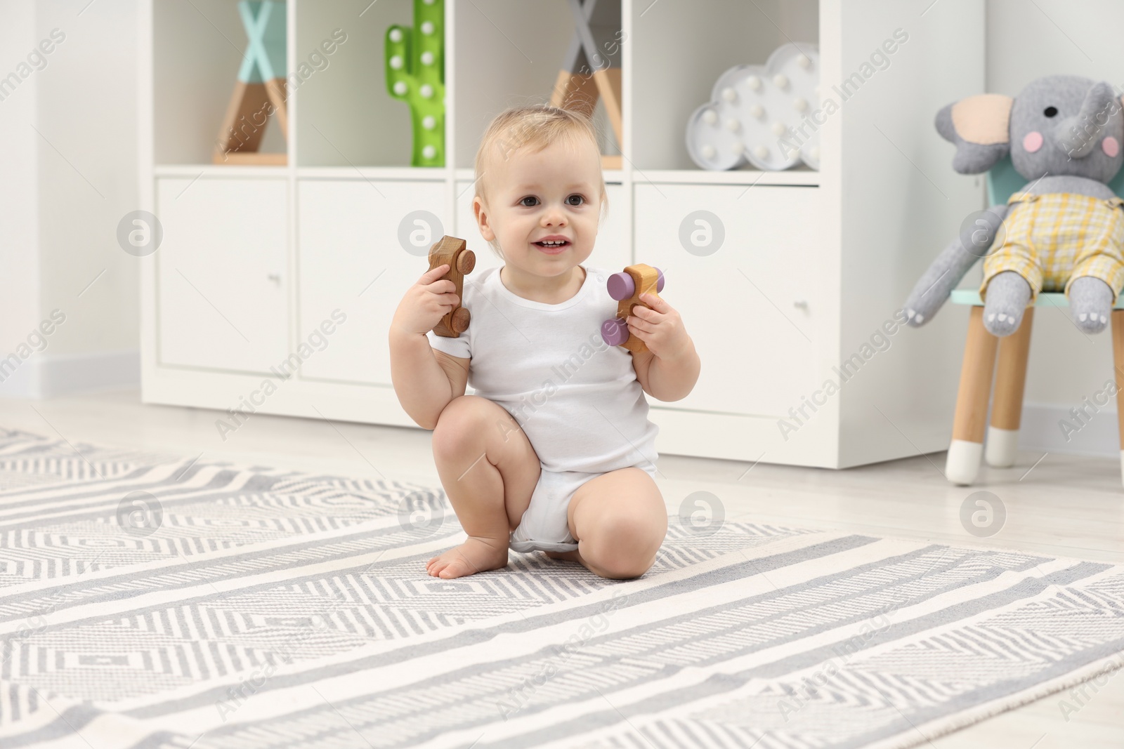 Photo of Children toys. Cute little boy playing with wooden cars on rug at home