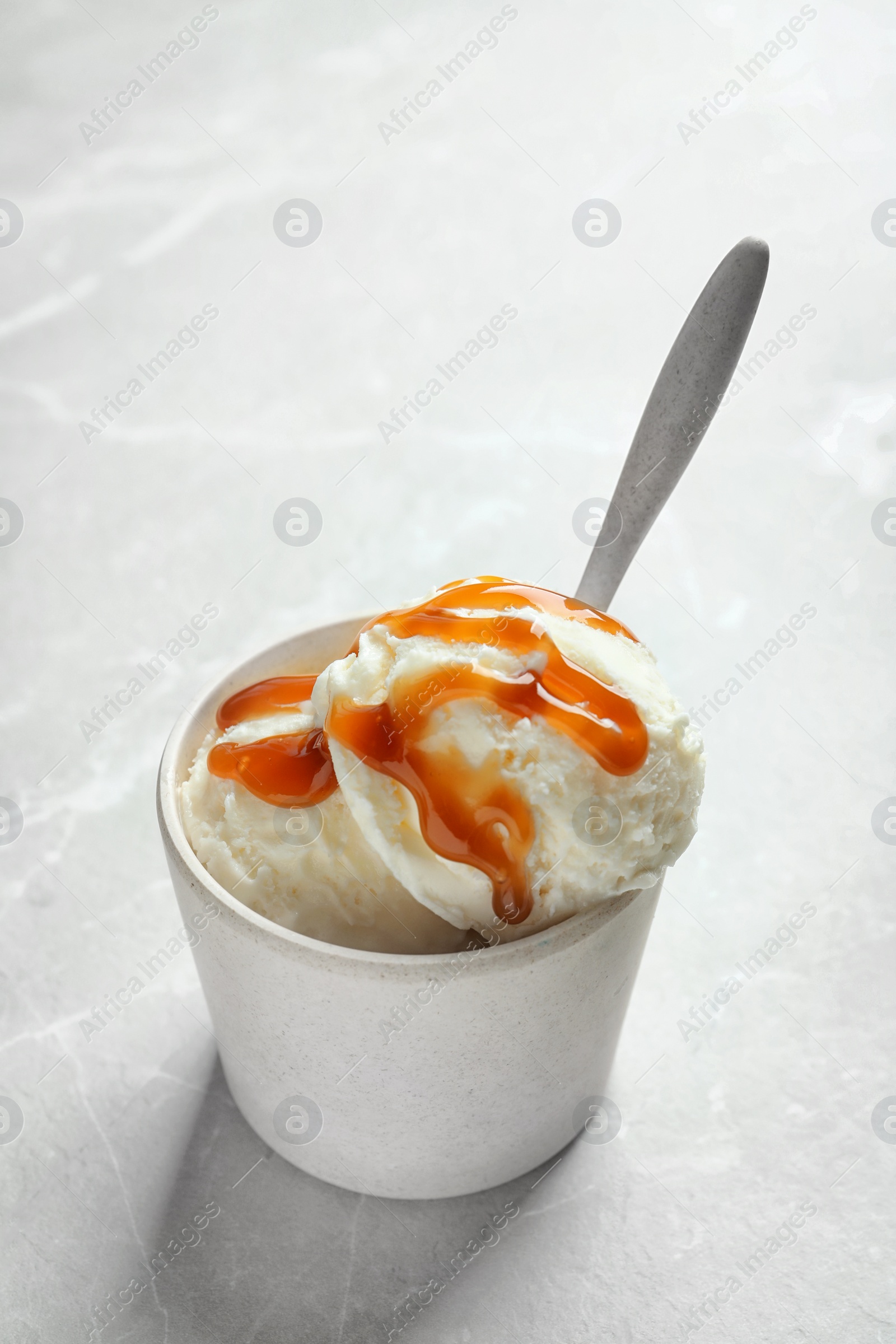 Photo of Bowl with caramel ice cream on light background