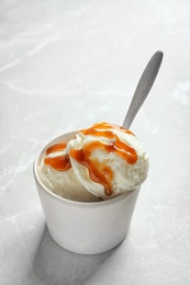 Bowl with caramel ice cream on light background